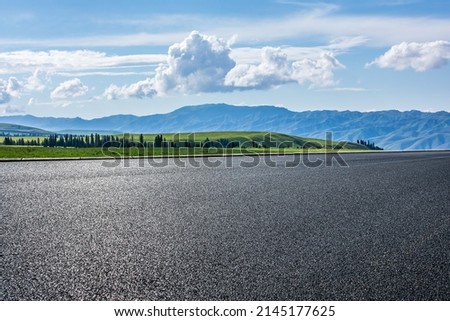 Empty asphalt road and green grassland and mountain under blue sky  Royalty-Free Stock Photo #2145177625