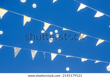 balloons flying in the blue sky through the hanging flags of a country festival