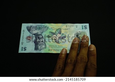 1 BND, One Brunei darussalam Dollar money concept, holding by businessman, isolated on black background