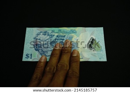 1 BND, One Brunei darussalam Dollar money concept, holding by businessman, isolated on black background