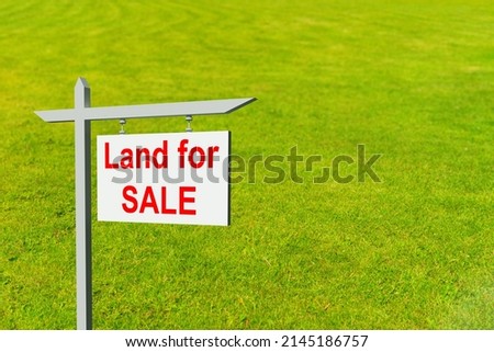 Land for sale sign. Illustration on theme of real estate. Purchase of a land plot. White sign for sale on a lawn background. Concept - Plot of land for sale by a realtor. Realtor business.