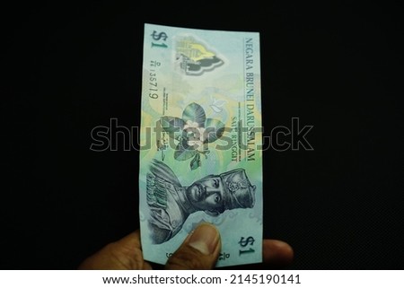 1 BND, One Brunei Darussalam dollar money concept, holding by businessman, money concept isolated on black backgorund