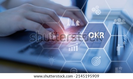 OKR text (Objectives, Key and Results) Working on computer with OKR, business goal, process, outcome. Focused on common goals. Achieve business growth by flexible management. Drive performance growth. Royalty-Free Stock Photo #2145195909