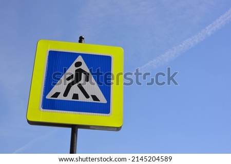 Pedestrian crossing sign on blue sky background
