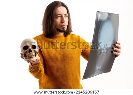 Frowned European man holds skull and x-ray, looks closely at the x-ray white background studio shot isolated . High quality photo