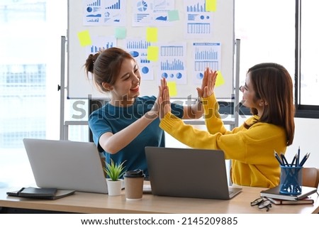 Young business people giving high fives each other for celebrating victory together.