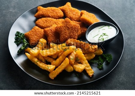 Fish Chips british fast food. Fish Sticks with french fries set on black plate on black table background. Traditional British authentic street food or takeaway food. Mock up with space for text.