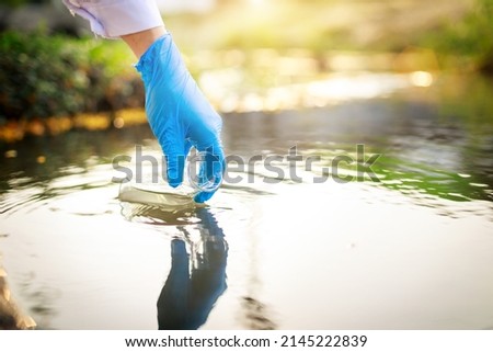 water pollution in the pond, river, lake, sea concept. Scientist takes samples of factory wastewater in a test tube. Close up the hand.