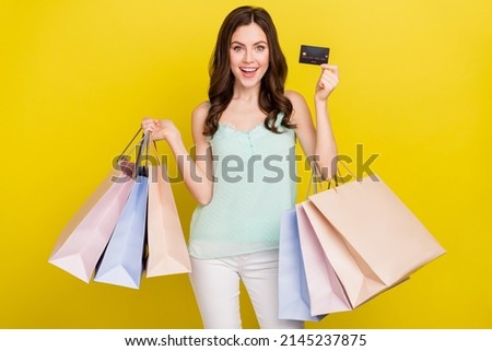 Photo of cute good mood female buy clothes online using her credit card wireless transaction isolated on yellow color background
