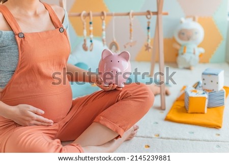 Pregnancy family planning budget. Cost of having a child. Pregnant woman holding piggy bank shopping newborn toys and nursery decor with savings. Maternity leave benefits Royalty-Free Stock Photo #2145239881