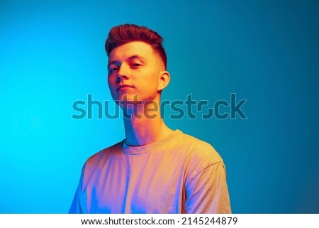 Studio shot of young emotional man, student posing isolated over blue studio background. Concept of wow emotions, facial expression, youth, action and ad