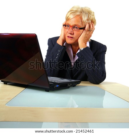 Computer Problems A businesswoman in her sixties in front of a laptop shocked with her hands on her head. Isolated over white.