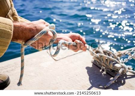 strong hands pulling hard on some ropes and moorings of a ship at the dock Royalty-Free Stock Photo #2145250613