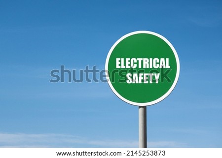 'Electrical safety' sign in green round frame. Clear blue sky is on background