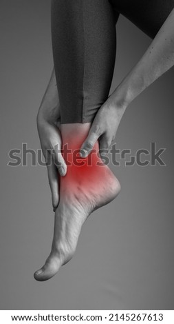 Ankle pain. Woman suffering from leg pain. Injury, sprain ligaments, arthritis symptoms. Health care, orthopedic problems and medicine concept. Black and white. High quality photo