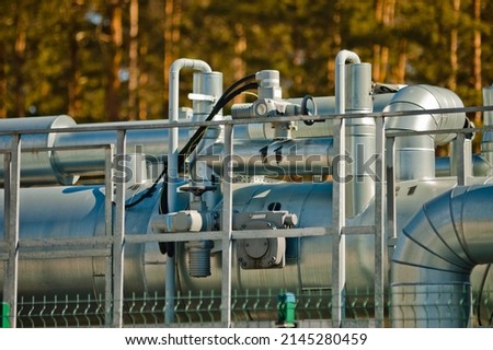 pipeline against the background of green trees and blue sky, in the photo pipes of various shapes and measuring instruments on them.