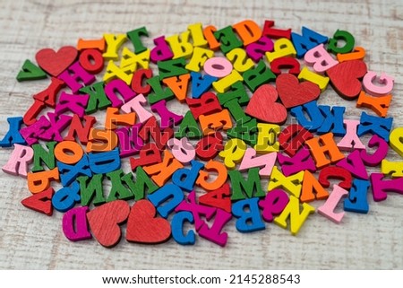 pile of multi-colored small wooden letters for primary education.  English letters in a chaotic order on wooden table