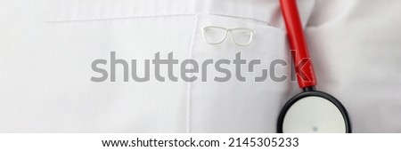 Eyeglass shape icon hanging on ophthalmologist gown closeup