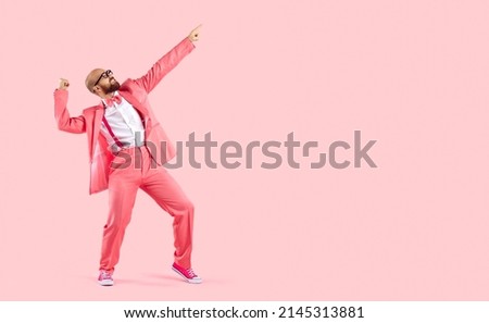 Cheerful successful man dancing funny making movements winner isolated on pink background. Funny man in pink formal suit celebrates his success having fun at copy space. Full length. Banner. Royalty-Free Stock Photo #2145313881