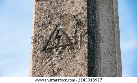 Electricity warning signal carved in concrete pillar