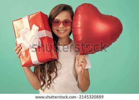smiling teen girl in sunglasses hold gift box and valentines party heart balloon, happy childhood.
