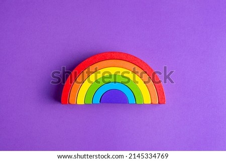Colorful Waldorf wooden human figure rainbow in a montessori teaching pedagogy on purple background, kid play concept