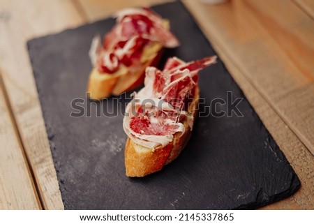 Two gourmet canapes of raw Iberian ham
 Royalty-Free Stock Photo #2145337865