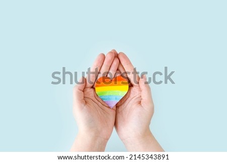 International Day Against Homophobia, Transphobia and Biphobia. May 17. Stop Homophobia. Heart with rainbow LGBT flag in the hands on a blue background. banner or greeting card. Royalty-Free Stock Photo #2145343891