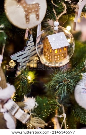 toy house christmas decorations on fir branches close-up glass balls price tags store decor showcase beautiful blur