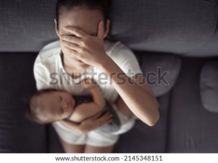 motherhood, multi-tasking and family concept. Tired mother having headache, stressed with baby child at home