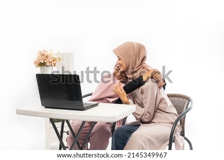 female muslim comforting her sad friend while working on her laptop