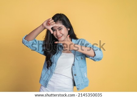 young woman looking from between fingers forming a frame
