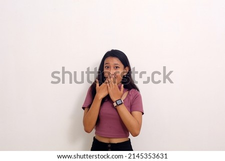 portrait of amazed and startled asian girl staring at camera speechless, holding hands on mouth