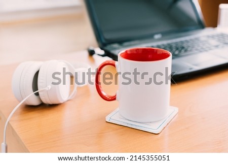 Workspace, distance learning or work. White cup of tea or coffee close-up on office desk with laptop and white headphones. Break concept. Empty Workplace.