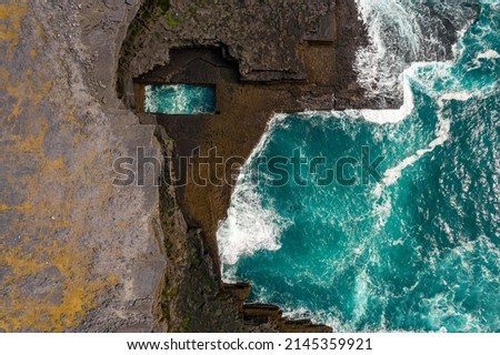 Aerial view on Poll na bPéist Wormhole, Inishmore, Aran Island. Ireland. Famous and popular tourist landmark. Natural basin in rough stone coast filled with ocean water. Blue ocean water. Royalty-Free Stock Photo #2145359921