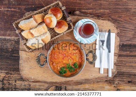 Ingredients in Menemen frying pan and on the table. Famous Turkish menemen dinner on table, made by eggs, pepper and tomatoes. Royalty-Free Stock Photo #2145377771