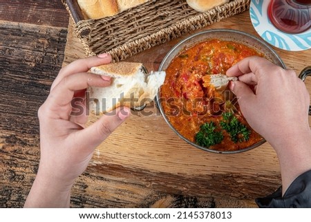Ingredients in Menemen frying pan and on the table. Famous Turkish menemen dinner on table, made by eggs, pepper and tomatoes. Royalty-Free Stock Photo #2145378013