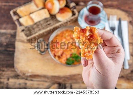 Ingredients in Menemen frying pan and on the table. Famous Turkish menemen dinner on table, made by eggs, pepper and tomatoes. Royalty-Free Stock Photo #2145378563