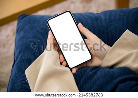 Close-up image, Relaxed woman sitting on a comfy sofa and using smartphone. smartphone white screen.