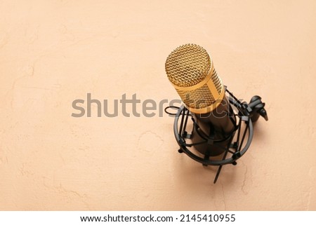 Modern microphone with stand on beige background