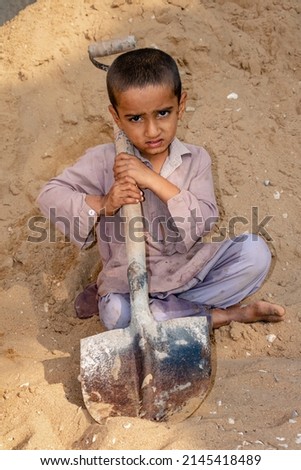 child boy working with the shovel on a construction site