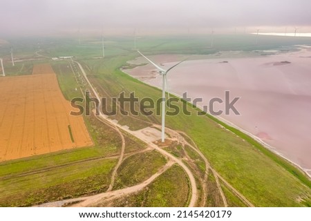 Amazing aerial view, of wind turbine near pink lake. Ukraine, lake Sivash, Kherson region.