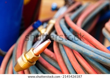 Equipment for gas cutting of metal. Gas burner on gas hoses, cylinder with oxygen and acetylene. Royalty-Free Stock Photo #2145426187