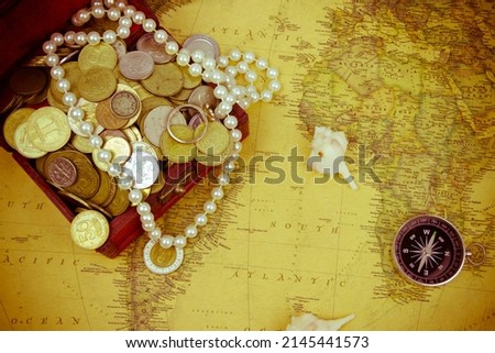 Treasure chest with jewelry and coins, compass and shells on a vintage map