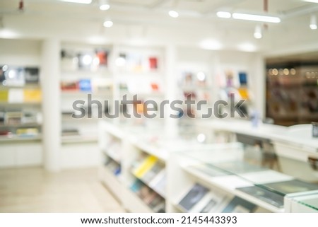 Abstract blurred of the interior of the public library with wooden tables, chairs and books in bookshelves. use for background or backdrop in book shop business or education resources concepts