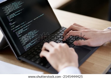 Asian programmer writing code on a laptop Royalty-Free Stock Photo #2145444425