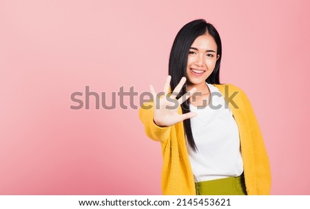 Asian portrait beautiful cute young woman teen smiling doing show stop sign gesture with palm of hand but happy face studio shot isolated on pink background, female doubt with copy space