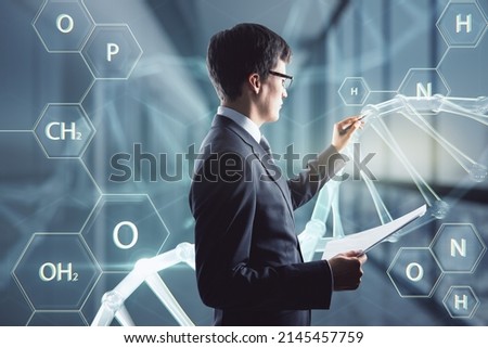 Medicine, bioengineering and technology concept with serious man in black suit using stylus working with digital touch screen with DNA and chemical compounds signs Royalty-Free Stock Photo #2145457759