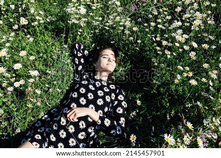 beautiful woman traveler lies in the grass of chamomile flowers