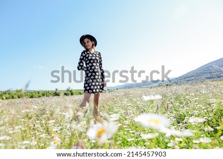 beautiful woman traveler walks through a field of chamomile flowers